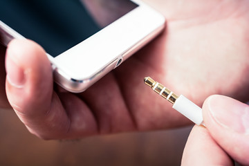 Headphone Jack Of A White Smartphone Gets Plugged In A White Headset Cable
