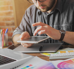 Young creative artist of web design in hat with graphic tablet in modern loft office