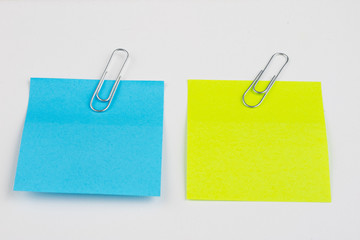 Blank colored sticky notes with clips. Office accessories for listing and memorizing on the table. White background.