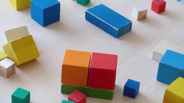 Children and parent playing together with wooden bricks. Children constructing house from colored elements. Bright toy building - real estate theme. Closeup view.