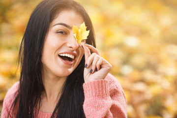 Very beautiful young woman on the autumn background. Close up portrait of smiling young pretty girl in the fall time.