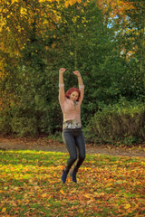 Happy young woman jumping in autumn park