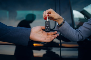 Woman give cars key to man. Hands hold car keys. Car rental