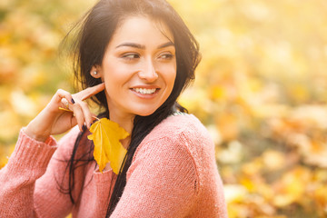 Very beautiful young woman on the autumn background. Close up portrait of smiling young pretty girl in the fall time.