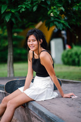 Portrait of Asian Chinese girl with mobile phone and skateboard in a skate park 