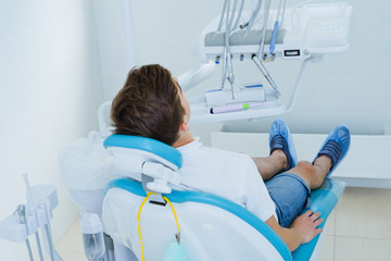 Dental caries prevention. Teenage boy at the dentist's chair during a dental procedure