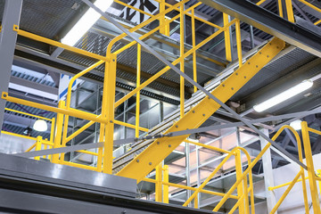 Metal staircase, with yellow railings and metal steps.