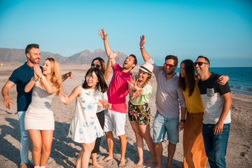Obraz premium Multicultural group of friends partying on the beach - Young people celebrating during summer vacation, summer time and holidays concepts