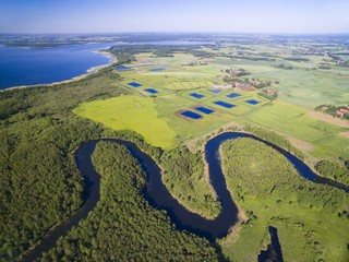 Meander of Wegorapa river flowing across wetlands, Mazury, Poland. Mamry Lake in the background