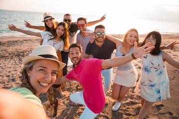 Happy multiracial young people are making a selfie at the beach while they are in a summer party....