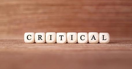 Word CRITICAL made with wood building blocks