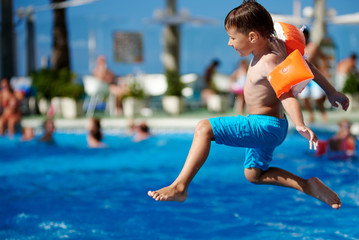 Boy having fun jumping into the pool. - 210585602