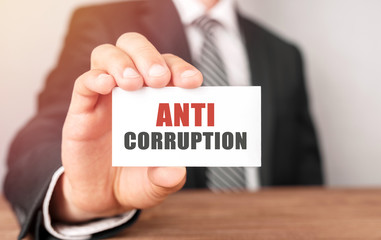 Businessman holding a card with text Anti Corruption