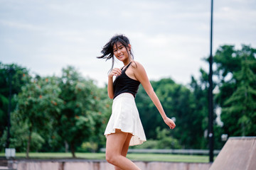 A young Chinese Asian millennial stunningly and gracefully smiling into the camera. She enjoys twirling and whirling under the sun.