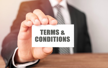 Businessman holding a card with text Terms And Conditions