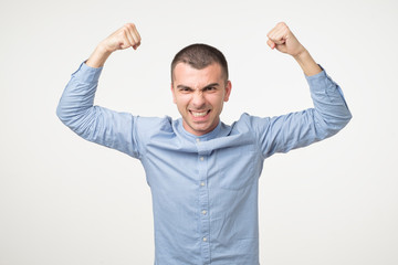 Portrait of very excited young hispanic man, celebrating victory with raised hands and screaming