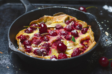 Cherry Dutch Baby, Puff German Pancake on Vintage Pans and Dark Background, Homemade Summer Dessert