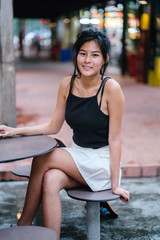  Portrait of a young, attractive Chinese Asian skater girl. The girl is sitting alone at the hawker...