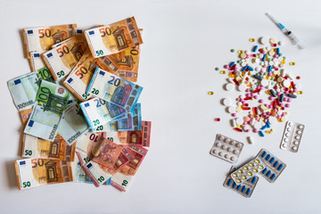 Money and pills. Pills of different colors on white background.