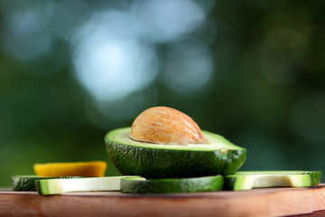 Avocado on blurred green bokeh background, cut avocado on a wooden board, exotic fruit for salad,...