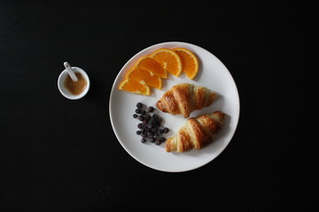 A french breakfast with croissants, oranges, berries and a shot of espresso