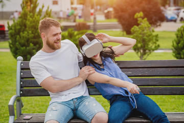 A young couple plays a game using virtual reality glasses on the street.