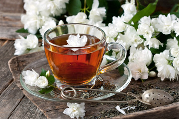 Cup of green tea with jasmine flowers on wooden background.
