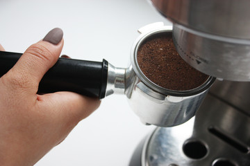 Female hand attaching espresso portafilter to the coffee machine