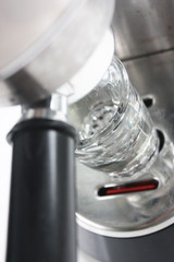 Espresso shot glass underneath an espresso machine 