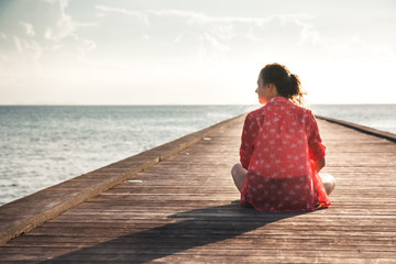 Pensive young woman tourist enjoy her life sitting on pier beach with infinity view copy space 