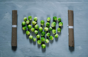 Food background of briussel cabbage in the shape of heart and Japanese noodles, top view, copy space, closeup. Diet, pure food or the concept of vegetarian food.