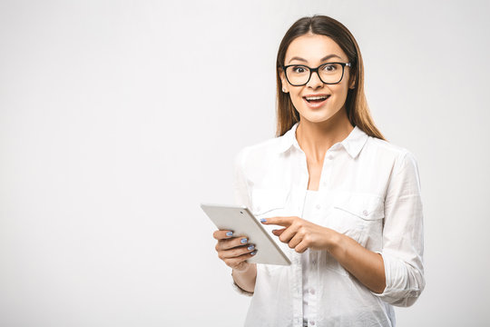 Portrait of a beautiful surprised woman using tablet computer isolated on a white background and looking at camera. Free space for text.
