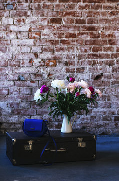 Loft style interior with bunch of flowers and retro suitcase decoration, copy space on brick wall