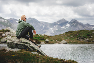 Mann sitzt auf Felsen an einem Bergsee nach dem Aufstieg