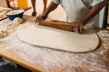 Baker kneading dough in a bakery. Traditional Bakery Concept.