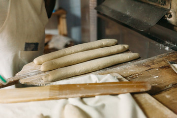 Baker is preparing the raw dough bread before baking in a wood oven. Traditional Bakery Concept.