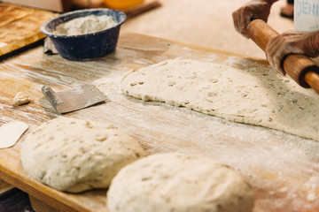 Male baker prepares bread. Baker kneading the dough with flour. Making bread. Rustic and traditional style of Bakery.