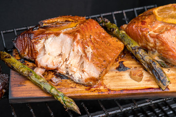 cedar plank salmon with lemon cooking on grill