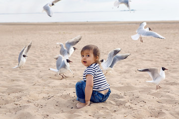 baby boy in striped sailor t-shirt running on the sandy beach