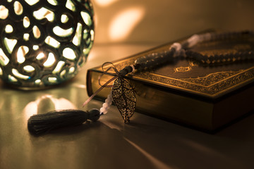 Koran and rosary on the white background with blue candle for Islamic concept. Holy book quran for Muslims holiday, Ramadan, Friday message and three months.