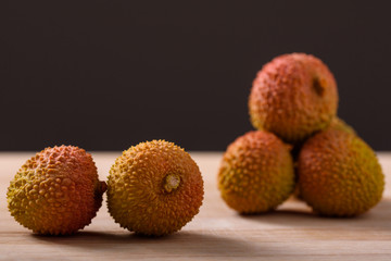 Natural lychee fruits with rough skin on a wooden surface