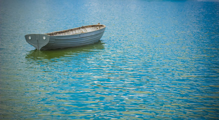 one small small boat on blue water surface background concept with empty space for copy or text