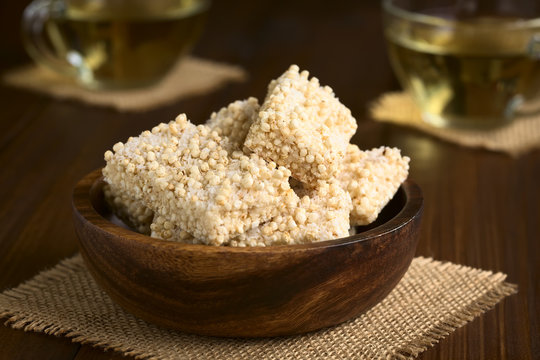 Baked marshmallow, popped quinoa and coconut bars in wooden bowl, photographed with natural light (Selective Focus, Focus on the front of the bar on the top)