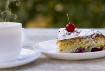 Вкусный кусок вишневого пирога на белой тарелке и белая чашка горячего чая с лимоном. Крупный план. Мокап.