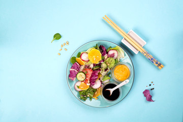 Fresh salad with fruits and greens on blue background