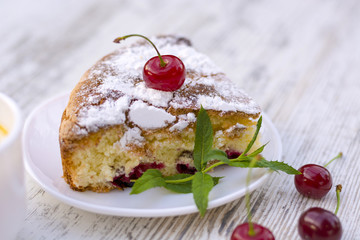 Вкусный кусок вишневого пирога на белой тарелке и веточка свежей мяты