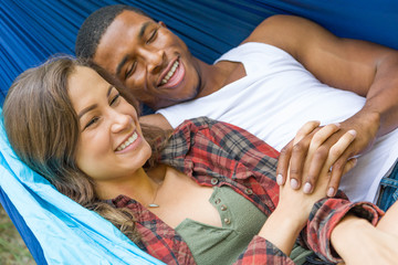 Affectionate African American Man with Hispanic Girl Laying in Hammock Outdoors