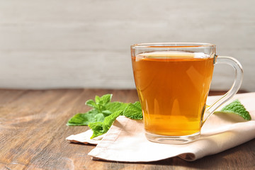 Cup with hot aromatic mint tea on wooden table