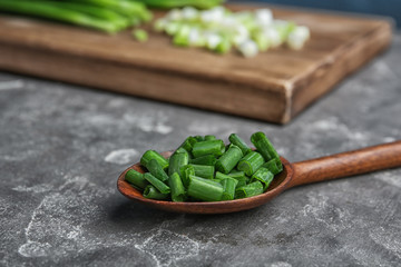 Spoon with chopped green onion on table