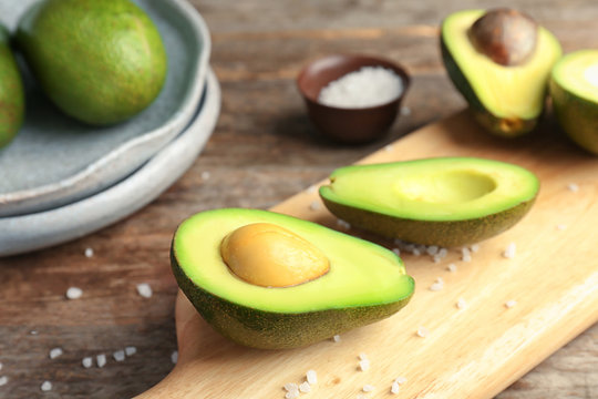 Wooden board with cut avocados on table